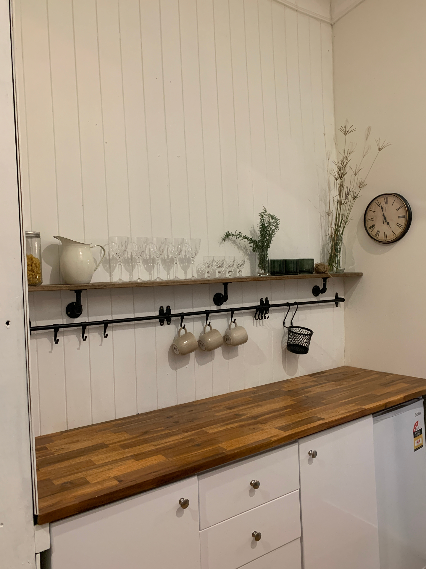Country kitchen with timber bench, crystal glasses and hanging mugs